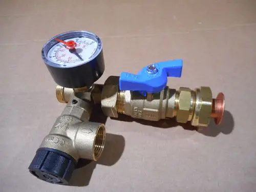 Brass valve assembly featuring a pressure gauge and a blue handle, part of a Remeha solar return group, set against a plain brown background.